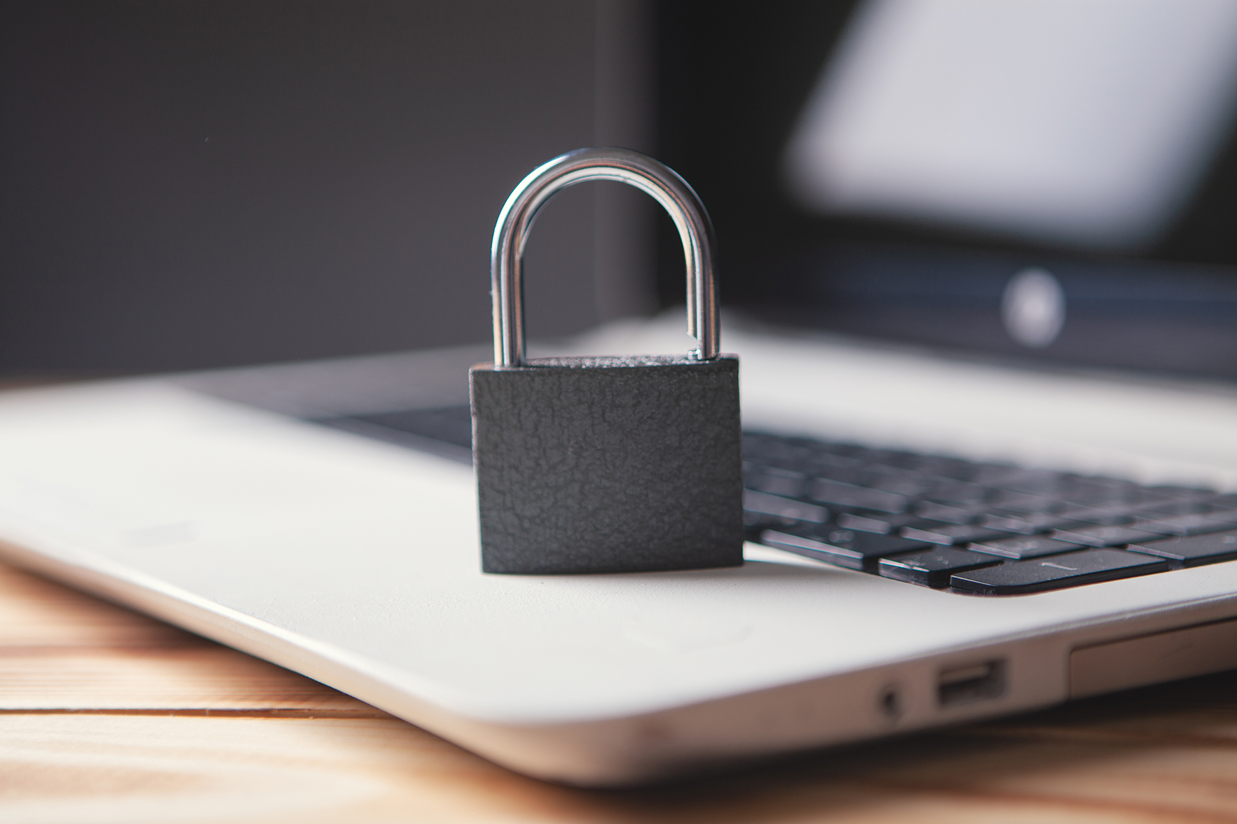 Aufgeklappter Laptop mit einem Sicherheitsschloss symbolisiert die IT-Sicherheit